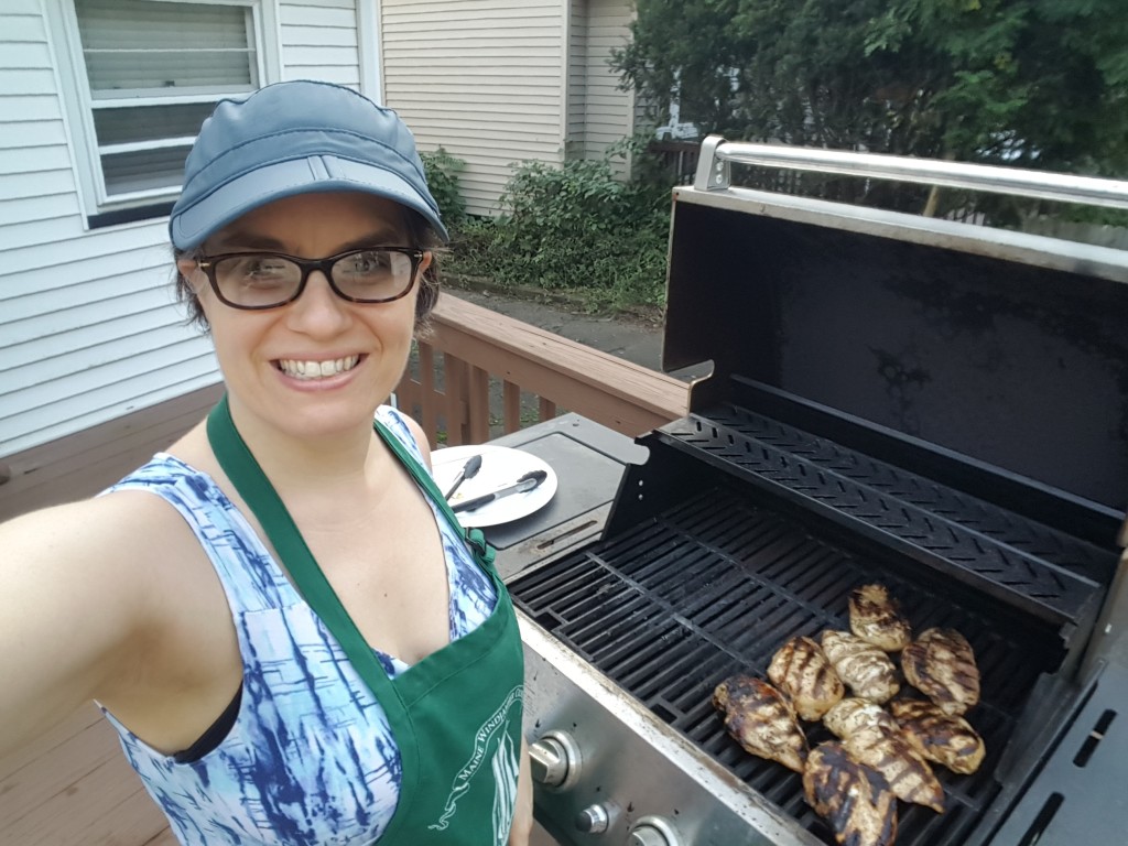 Karen grilling chicken on the deck (selfie) in blue hat and glasses